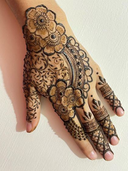 A beautiful semi bridal design featuring large floral motifs connected by a shaded arch. The fingers have crisscross patterns and the little finger has a delicate beaded design.
