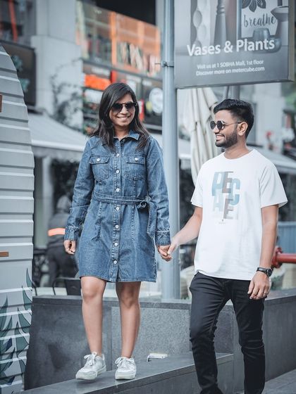 A duplicate of a happy, candid shot of a couple in denim, walking and holding hands in a modern urban area.