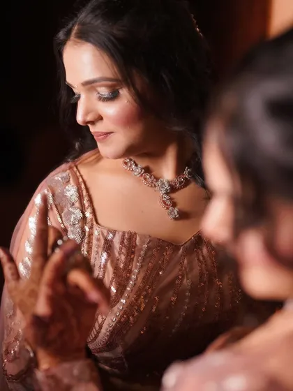 A candid moment between sisters or friends, showing the bride's beautiful makeup from a side profile.
