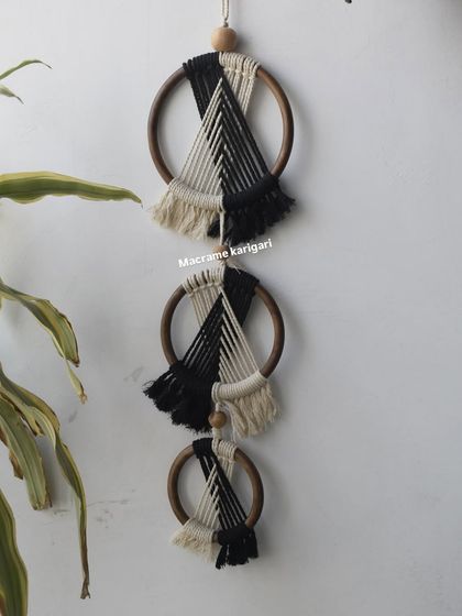Our 'Ringoz' wall art, a modern and minimalist design featuring three wooden rings with black and white macramé knotting. It's perfect for a contemporary boho look.