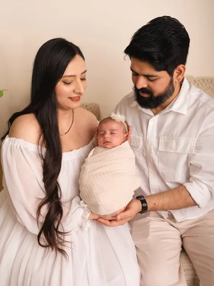 New parents admiring their sleeping baby, held between them. The focus is entirely on their new family and the love that fills the room.