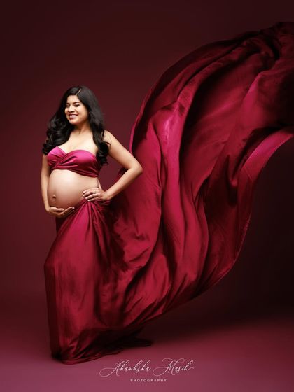 A joyful portrait in a flowing magenta gown, with the fabric tossed to create a beautiful sense of movement and celebration.