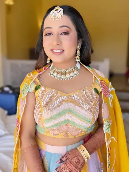 Minimal magic for Varija's Haldi or Mehendi. The makeup is fresh and colorful, with a pop of peachy-orange on the eyes to complement her yellow outfit.