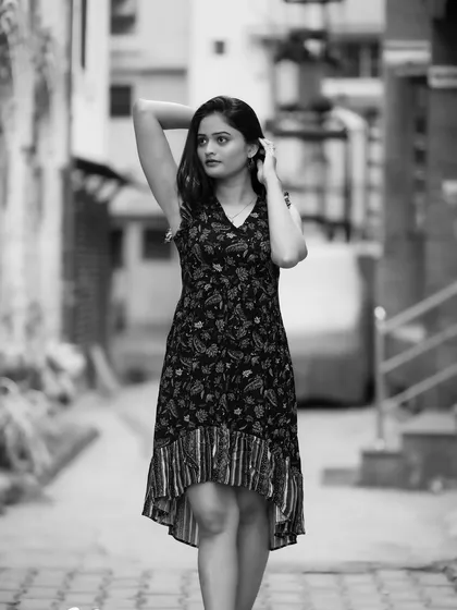 A classic full-body portrait in an urban alley. The black and white tones emphasize the textures of the location and her thoughtful pose.