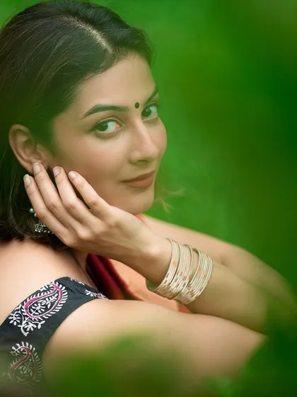 A creative close-up portrait framed by green leaves, focusing on the model's expression and accessories. This artistic approach helps a brand's visuals stand out.