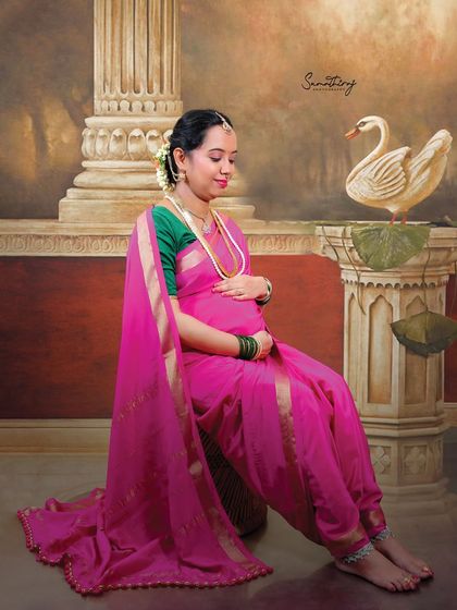 Inspired by the paintings of Ravi Varma, this portrait captures the mother-to-be in a thoughtful pose, draped in a pink saree. The classic setting with a swan prop adds to the artistic and timeless feel.