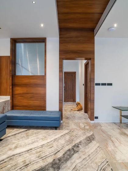 The family living area in "Vertical Nest," where our client's adorable Labrador, Leo, steals the spotlight. The space features warm wood paneling and a beautiful patterned marble floor.