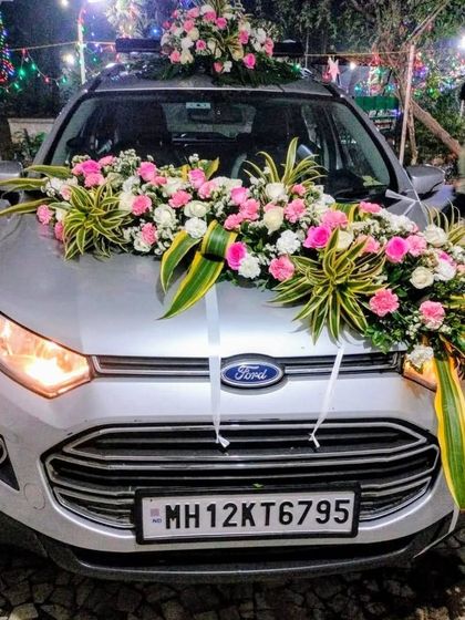 This Ford EcoSport is decorated with a lush arrangement of pink and white roses, complemented by variegated green leaves. The flowers are arranged to create a natural, flowing look across the bonnet.