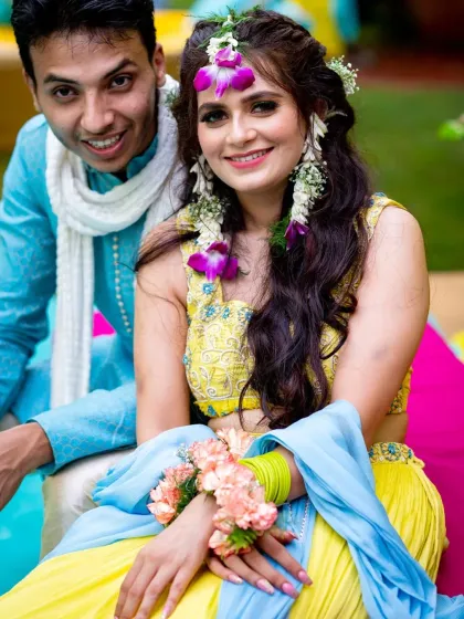 A happy couple portrait from their haldi ceremony, adorned with floral jewelry.