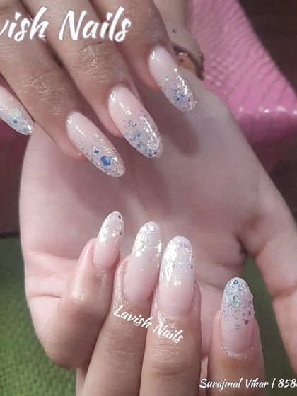 A delicate glitter fade on long almond nails using fine iridescent blue and silver glitter.