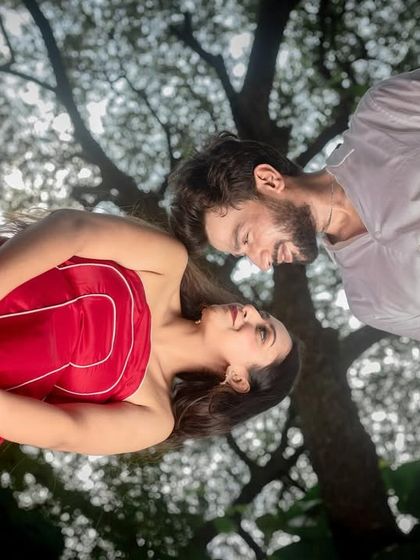A unique, low-angle shot looking up at the couple, with the trees creating a natural frame. This perspective adds an artistic and intimate feel.