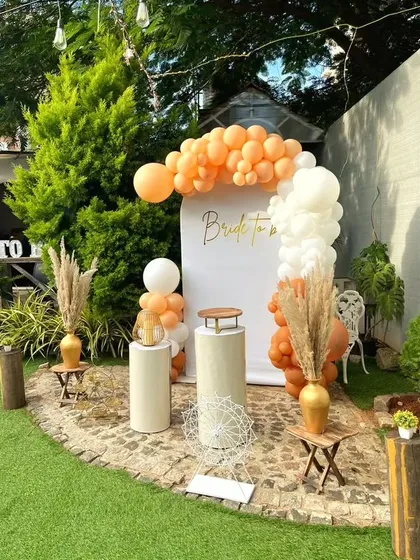 A simple and elegant "Bride to be" backdrop. The white panel is accented with a delicate peach and white balloon arrangement and pampas grass for a modern, minimalist look.