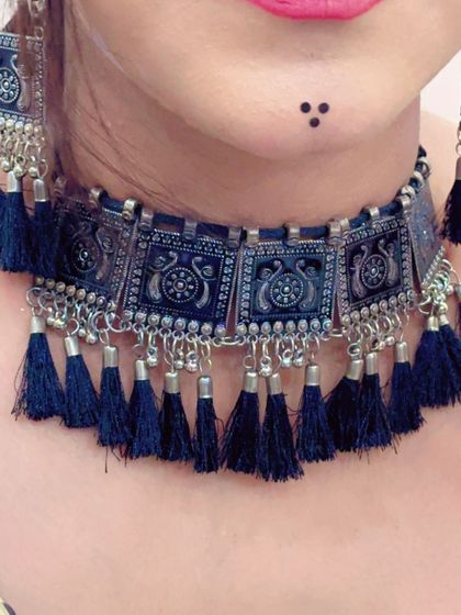 A close-up of a black tassel and oxidized silver choker necklace, a very popular style for Navratri.