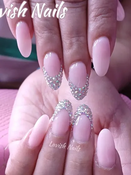 Demonstrating understated elegance, this design features soft pink almond nails with accent nails adorned with a delicate cascade of brilliant-cut stones at the cuticle.