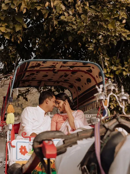 An intimate close-up of the couple inside a horse-drawn carriage, framed by the lush green trees, creating a private and romantic moment.