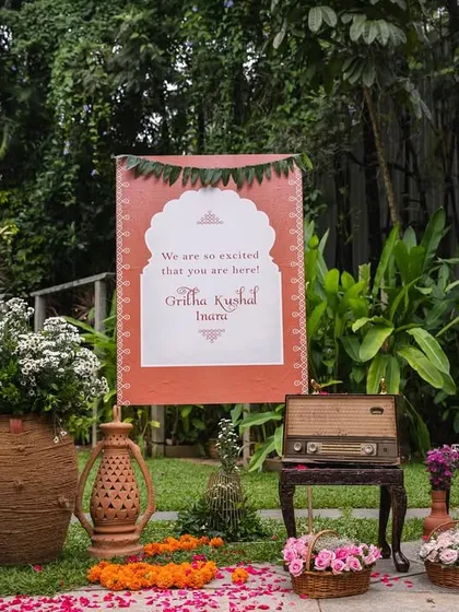 A personalized welcome sign for little Mitharv's naming ceremony. The decor featured rustic elements like a vintage record player and terracotta pots to evoke the charm of a 1990s South Indian village.