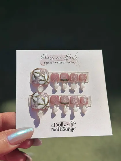 This press-on toe nail set features delicate, hand-painted floral art on the big toe, paired with shimmery pink on the others.