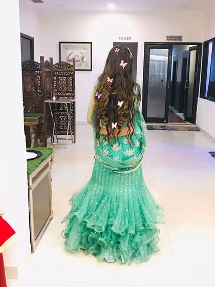 A back view of the sea-green lehenga, showing off a beautiful hairstyle with butterfly clips.