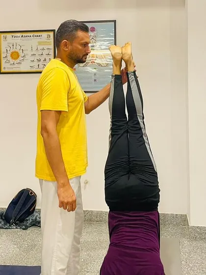 A teacher assists a student with her headstand alignment. This hands on correction is a vital part of learning to teach and practice asanas correctly.