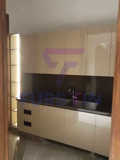 This image showcases the secondary wet area of the kitchen, complete with a built-in sink and backlit open shelving. The handleless, high-gloss cabinets contribute to the clean, modern design.