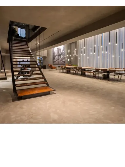 Another view of the gallery space, showing the dramatic steel and wood staircase. The architecture takes a relaxed approach, providing a versatile canvas for life and art.