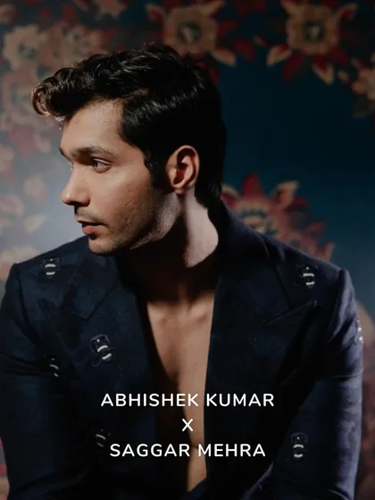 A profile shot of Abhishek Kumar, highlighting the sharp tailoring and the intricate pattern of the suit fabric. The mood is one of quiet confidence and modern elegance.