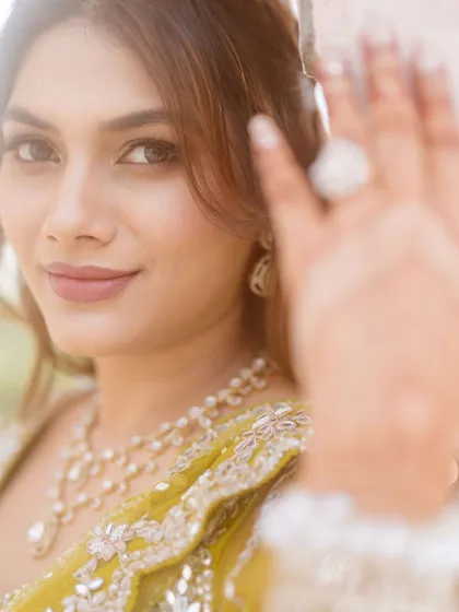 A creative shot of the bride, with her henna-covered hand in the foreground. Her makeup is soft and natural, with a pretty nude lip.
