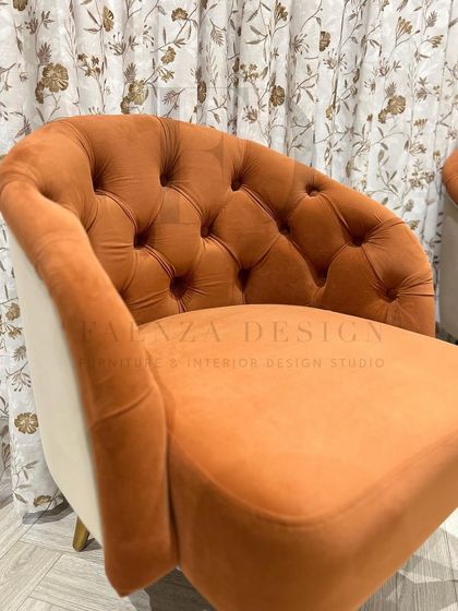 A set of two-tone accent chairs in a burnt orange velvet. The chairs feature a tufted back and a contrasting cream-colored exterior, creating a warm and inviting look.