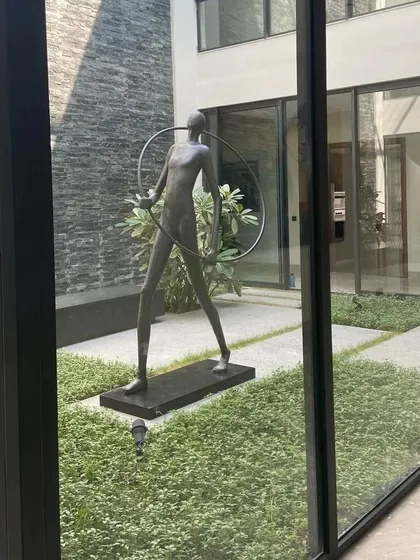 An angled shot of the courtyard sculpture, highlighting the play of light and shadow on its form and the surrounding stone wall. This demonstrates how we consider natural light in our designs to create evolving visual experiences.