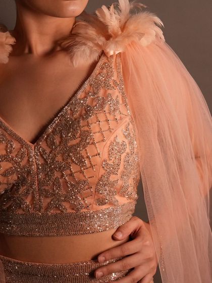 Another angle of the beautiful feather and beadwork on our peach cape set. It's a unique and high-fashion choice for any special occasion.