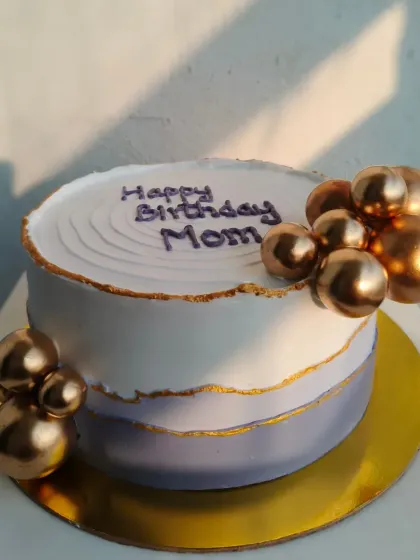 An elegant birthday cake for a mom, with a purple and white watercolor effect, gold leaf, and gold spheres.