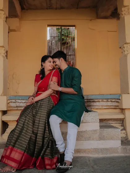 A couple sits on the steps of a temple structure, sharing a quiet moment of connection. The warm tones of the stone and their traditional attire create a beautiful, cultural pre-wedding portrait.