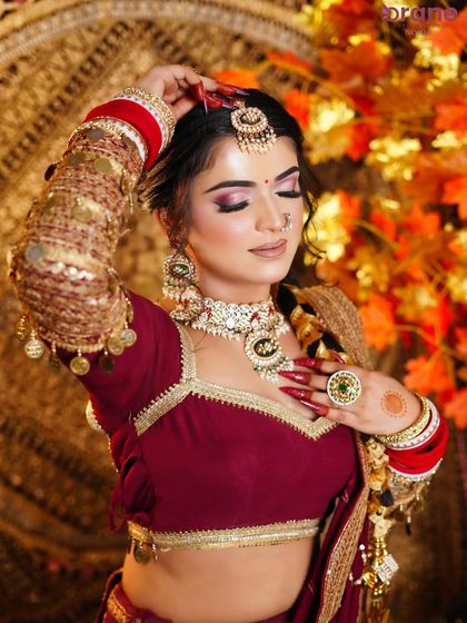 A soft, elegant pose that showcases the beautiful blend of colors in the makeup and the richness of the bridal outfit.