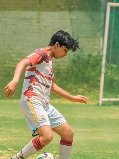 A player dribbles with focus, keeping his eyes on the ball and the field ahead.