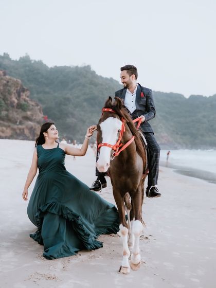 A fairytale-like pre-wedding photo on the beach with a horse. The deep green ruffled gown adds to the romantic and storybook feel of the moment.