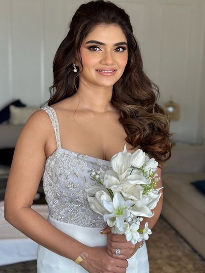 A beautiful bride ready for her white wedding or reception. Her look is soft and glamorous, with voluminous waves and a radiant smile.