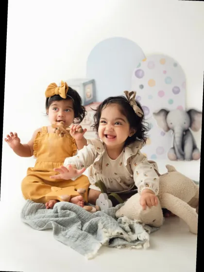 Twin girls clap and laugh during their adorable studio photoshoot. Capturing the energy of a twin toddler shoot is always a joy.