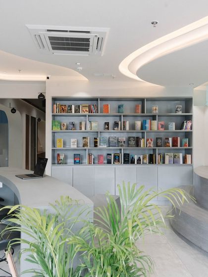 Another view of the library and reception area, showcasing the custom curved desk and open shelving that create an inviting and intellectual atmosphere.