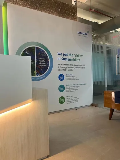 The reception area for Umicore prominently features their branding, which emphasizes sustainability. The design of the space reinforces this message through the use of natural materials and green elements.