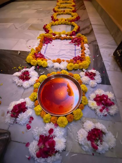 Another view of the ceremonial setup on the floor, featuring the thali with alta (red dye) and surrounded by intricate patterns made from fresh flowers.