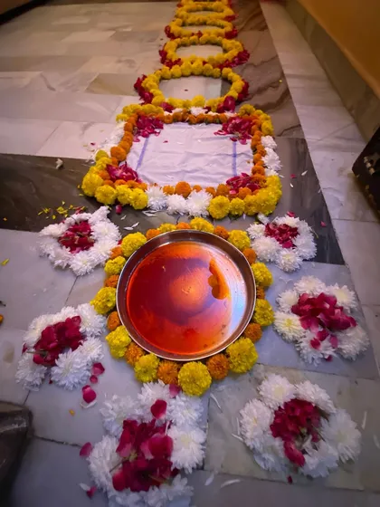 Another view of the ceremonial setup on the floor, featuring the thali with alta (red dye) and surrounded by intricate patterns made from fresh flowers.