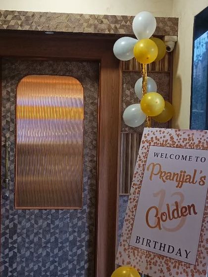 The entrance decor for a 13th birthday, featuring a custom "Golden Birthday" welcome sign and simple balloon bunches.