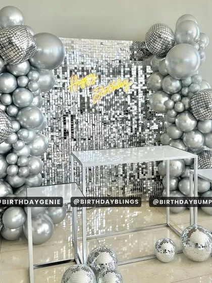 A stunning disco-themed birthday setup with a silver shimmer wall, disco ball balloons, and a chrome silver balloon frame.