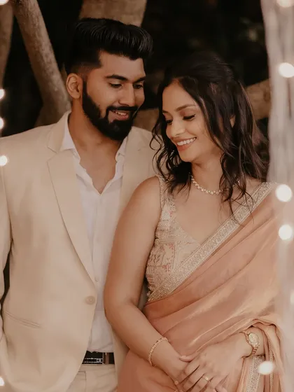 A sweet, smiling portrait of the newly engaged couple, framed by the soft glow of decorative lights.