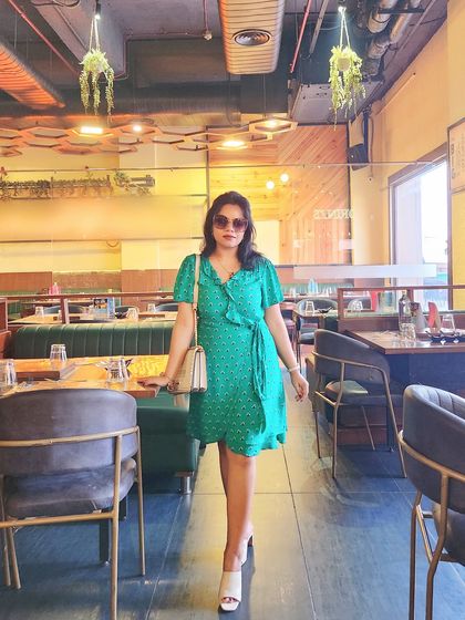 A full-length shot of the green wrap dress in a restaurant setting.