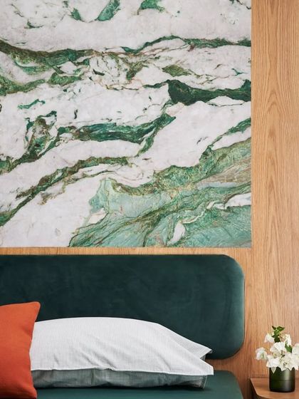 A close-up of the 'Forest of the Future' bedroom, where a luxurious Botanic Garden marble panel is paired with a deep green velvet headboard. This combination creates a rich, nature-inspired focal point.