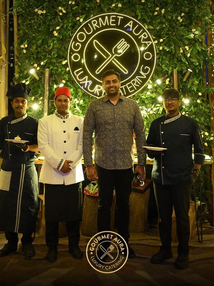 Our founder and chefs posing with a client in front of our beautifully lit green wall logo. We pride ourselves on building strong relationships with those we serve.