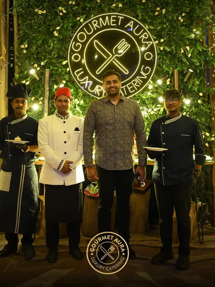 Our founder and chefs posing with a client in front of our beautifully lit green wall logo. We pride ourselves on building strong relationships with those we serve.