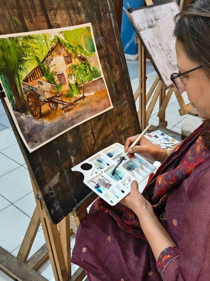 A student fully engaged in her watercolor painting, demonstrating the calm and focus that this medium inspires.