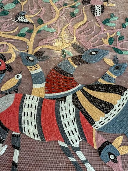 A close-up of a glass mosaic mural inspired by Gond art. Each piece of glass is hand-cut and placed to create a vibrant, textured narrative of deer and birds in an enchanted forest.